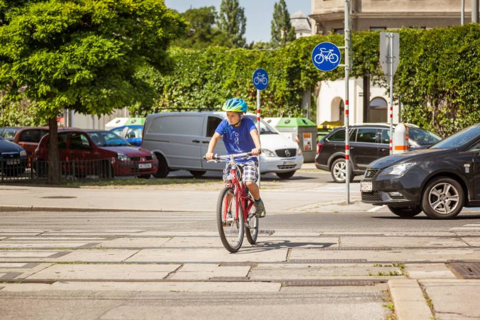 Ein Bub fährt mit dem Fahrrad über eine Kreuzung