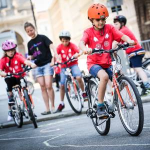 Kinder die beim Radkurs der Mobilitätsagentur spielerisch das Verhalten im Straßenverkehr beigebracht bekommen. Sie fahren mit Fahrrädern in einem Trainings-Parcours und machen Geschicklichkeitsübungen.