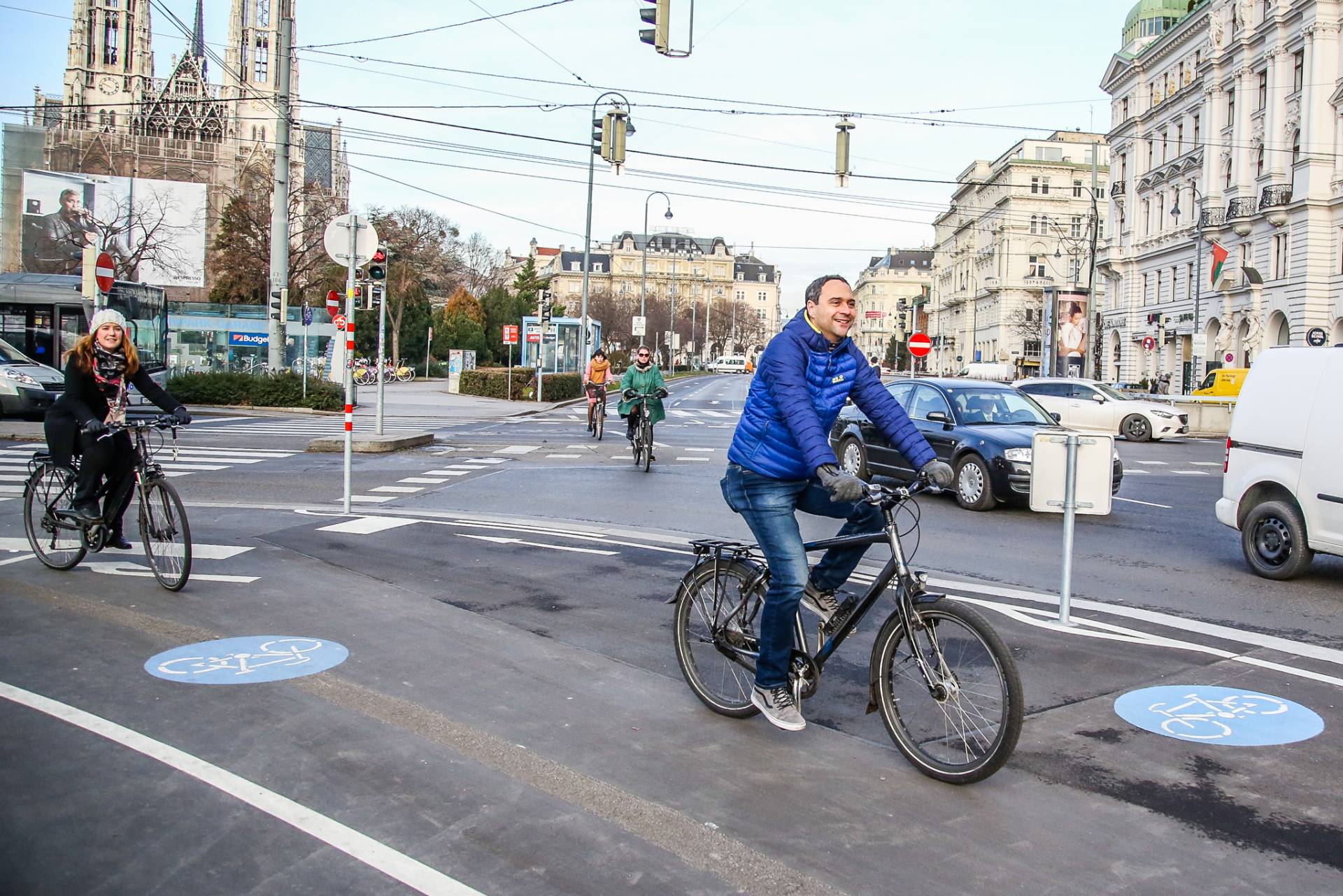 Vier Radfahrenden fahren am neuen Radweg am Jonas-Reindl. Im Hintergrund ist die Votivkirche. Foto: Christian Fürthner