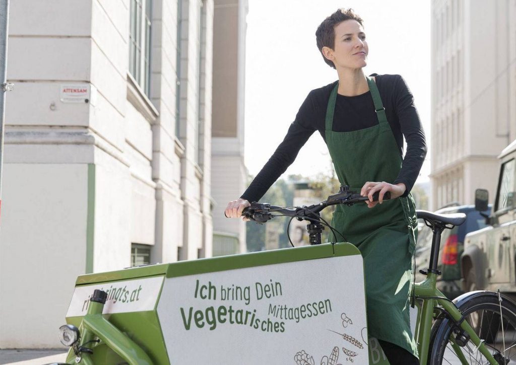 Rita Huber auf einem grünem Transportfahrrad. Foto: ritabringts.at