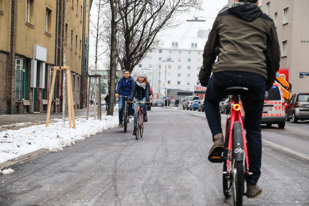 Ein Mann und eine Frau fahren auf dem neuen Radweg entlang der Favoritenstraße, ein Radfahrender kommt ihnen entgegen. Foto aufgenommen von Christian Fürthner.