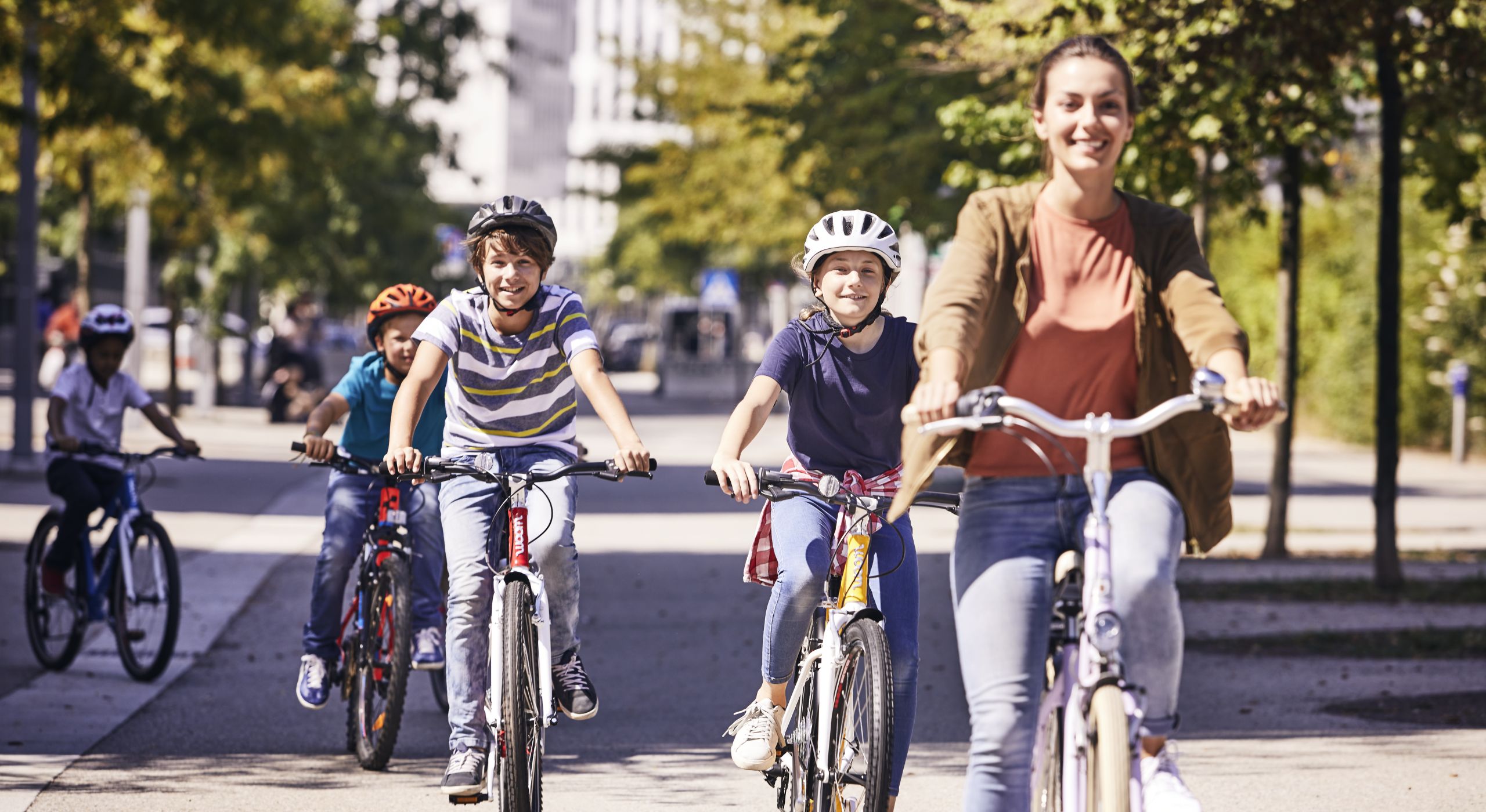 Drei Kinder und eine junge Frau sind gemeinsam auf ihren Fahrrädern unterwegs.