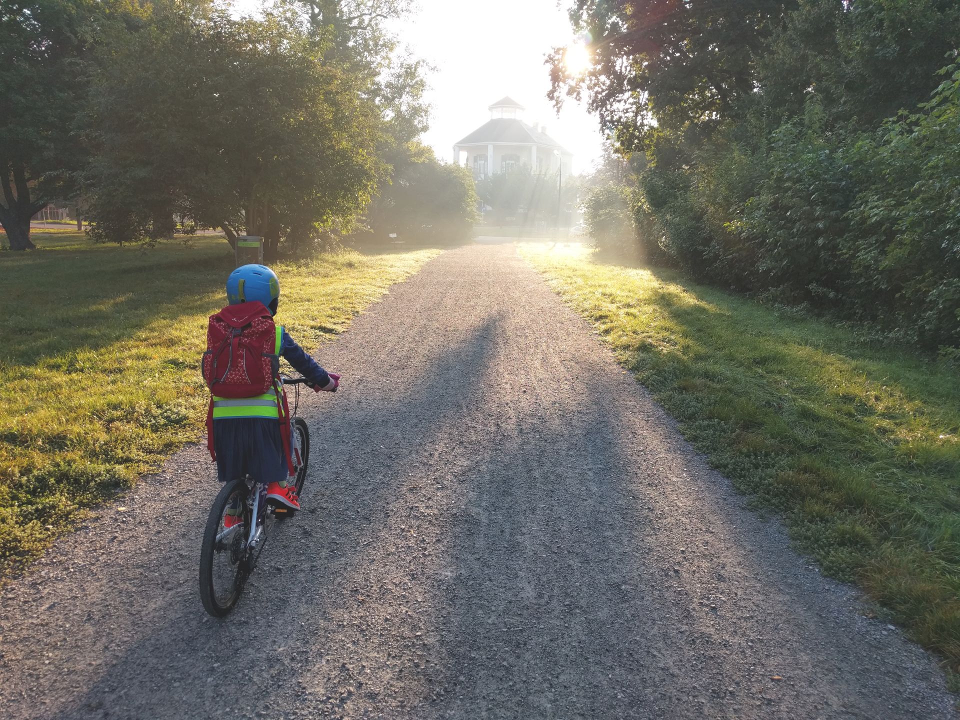 Ein Kind fährt mit einem Fahrrad einen Weg entlang. Es ist von hinten zu sehen.