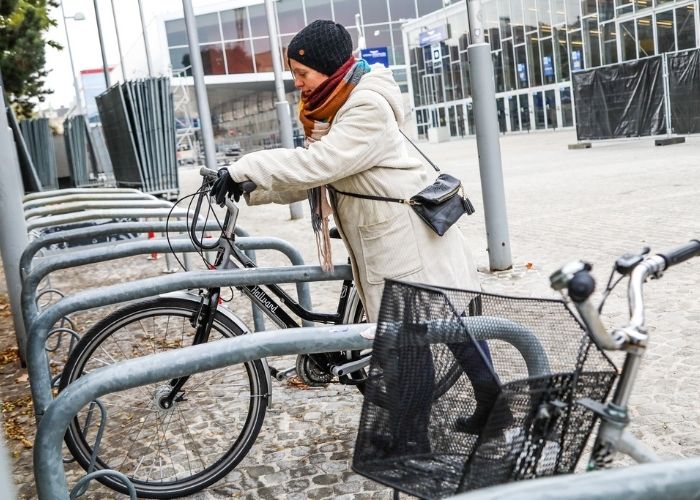 Radfahrerin stellt ihr Fahrrad im Radständer vor der Wiener Stadthalle ab.