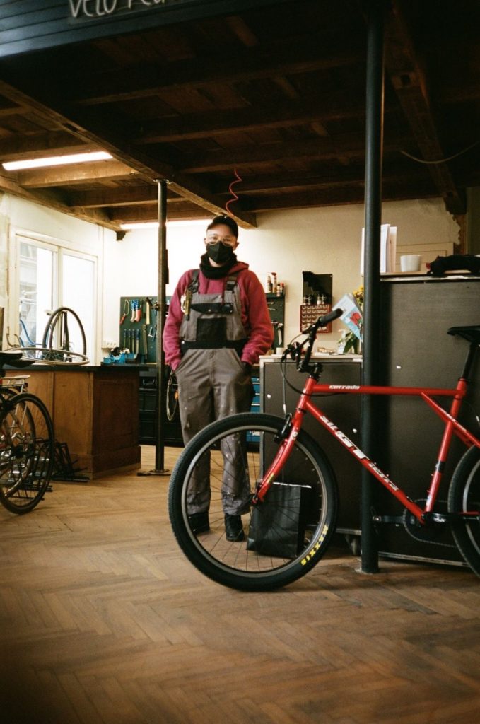 Mischa steht in der Fahrradwerkstatt, im Vordergrund ein rotes Fahrrad 